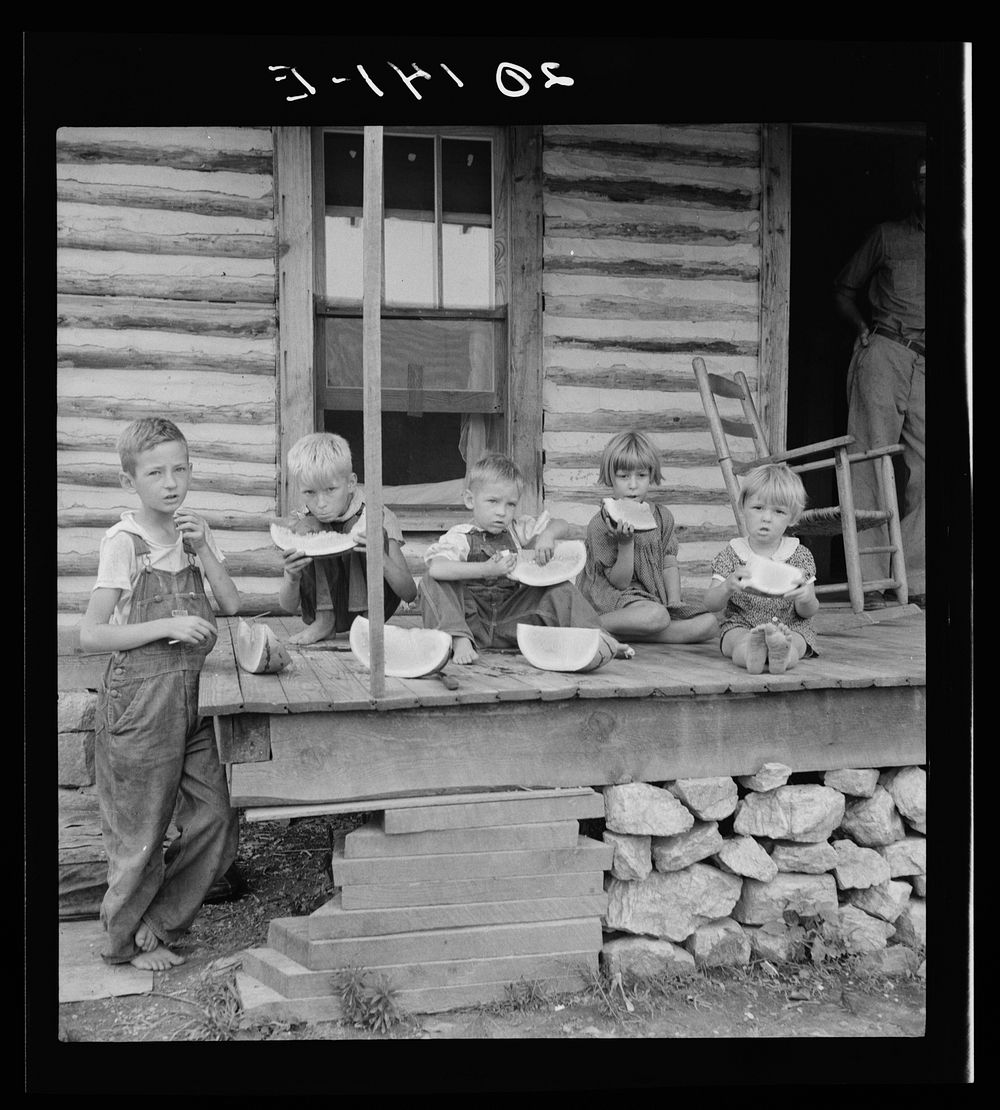 Millworker's children eating watermelon on porch of rented house. Six miles north of Roxboro, Person County, North Carolina…