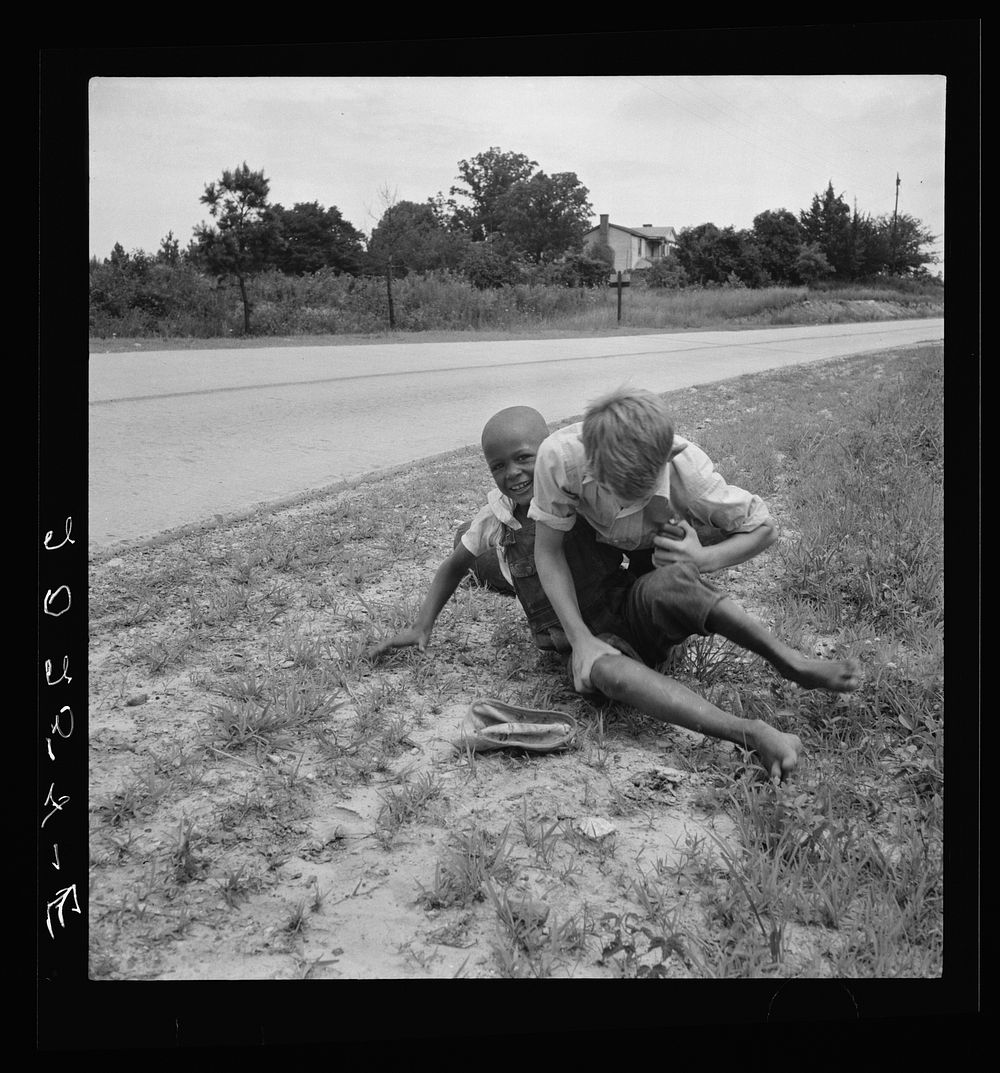 White and  boy wrestling by side of road. Person County, North Carolina. Sourced from the Library of Congress.