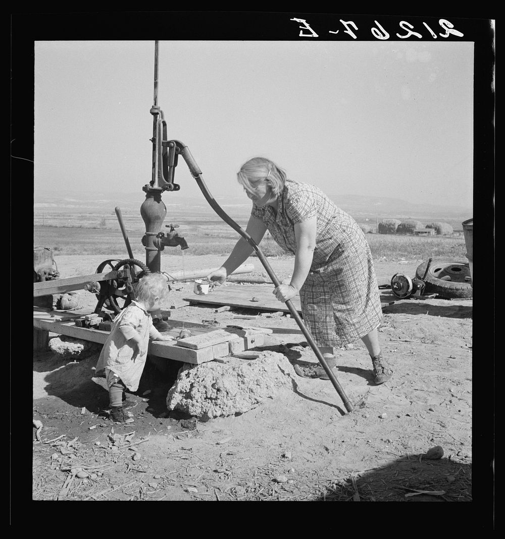 Mrs. Soper with youngest child at the well. Willow creek area, Malheur County, Oregon. Sourced from the Library of Congress.