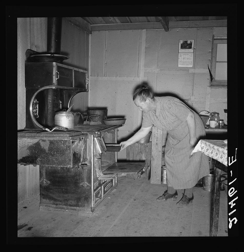 Mrs. Wardlow baking corn bread in her dugout basement home. Dead Ox Flat, Malheur County, Oregon. Sourced from the Library…