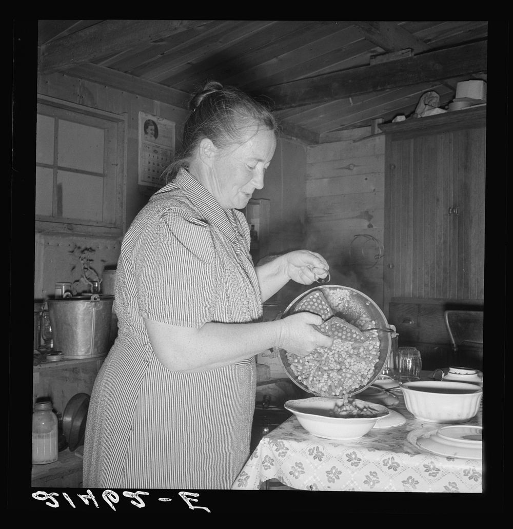 Mrs. Wardlow getting dinner after church in her basement dugout home. Dead Ox Flat, Malheur County, Oregon. Sourced from the…