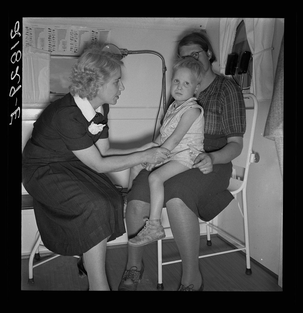 In trailer clinic. The nurse consults the migrant mother whose small boy is ailing. Merrill FSA (Farm Security…