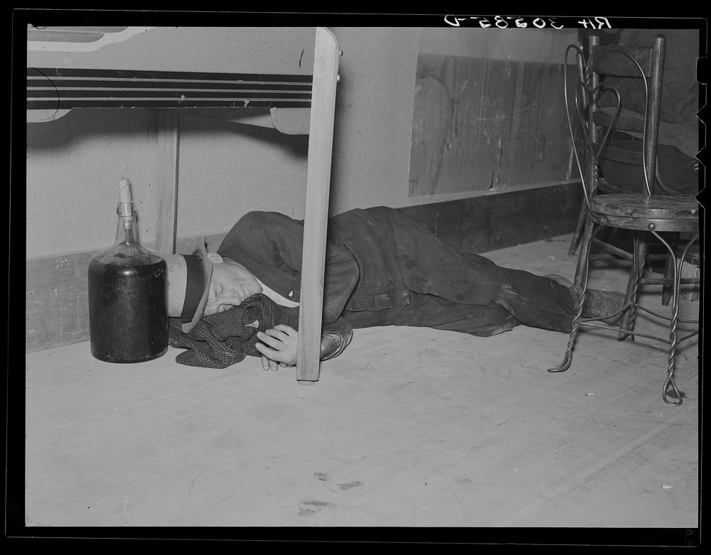 Lumberjack under the table in a saloon. Craigville, Minnesota by Russell Lee