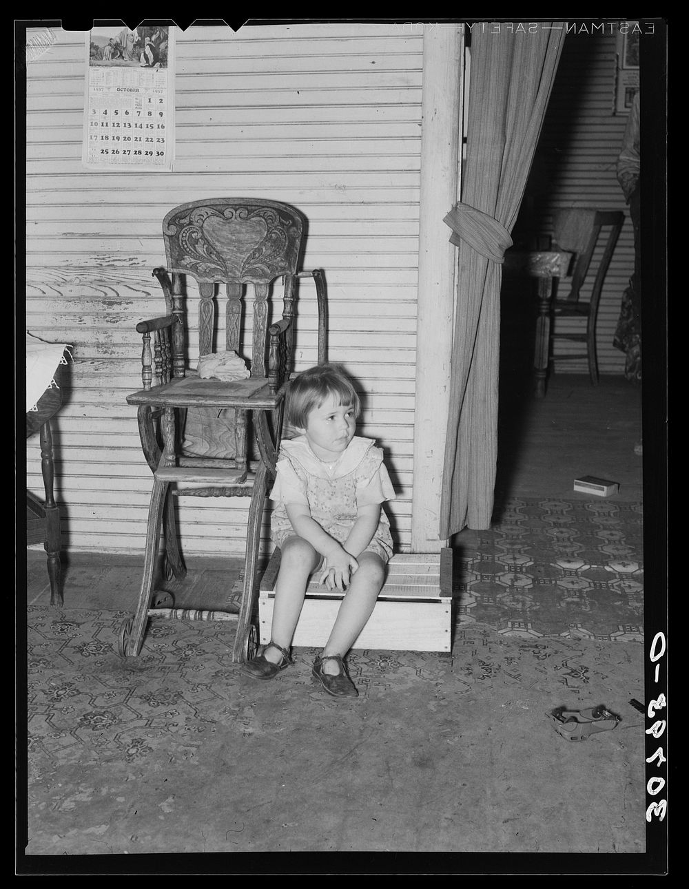 Daughter of farm laborer and old fashioned highchair. Williams County, North Dakota by Russell Lee
