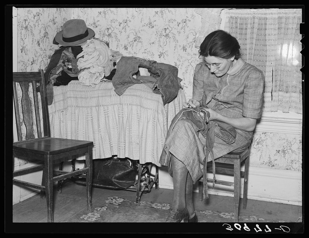 Mrs. Gallagher patching clothes for her children. Wife of former farmer, now living in Crosby, North Dakota by Russell Lee