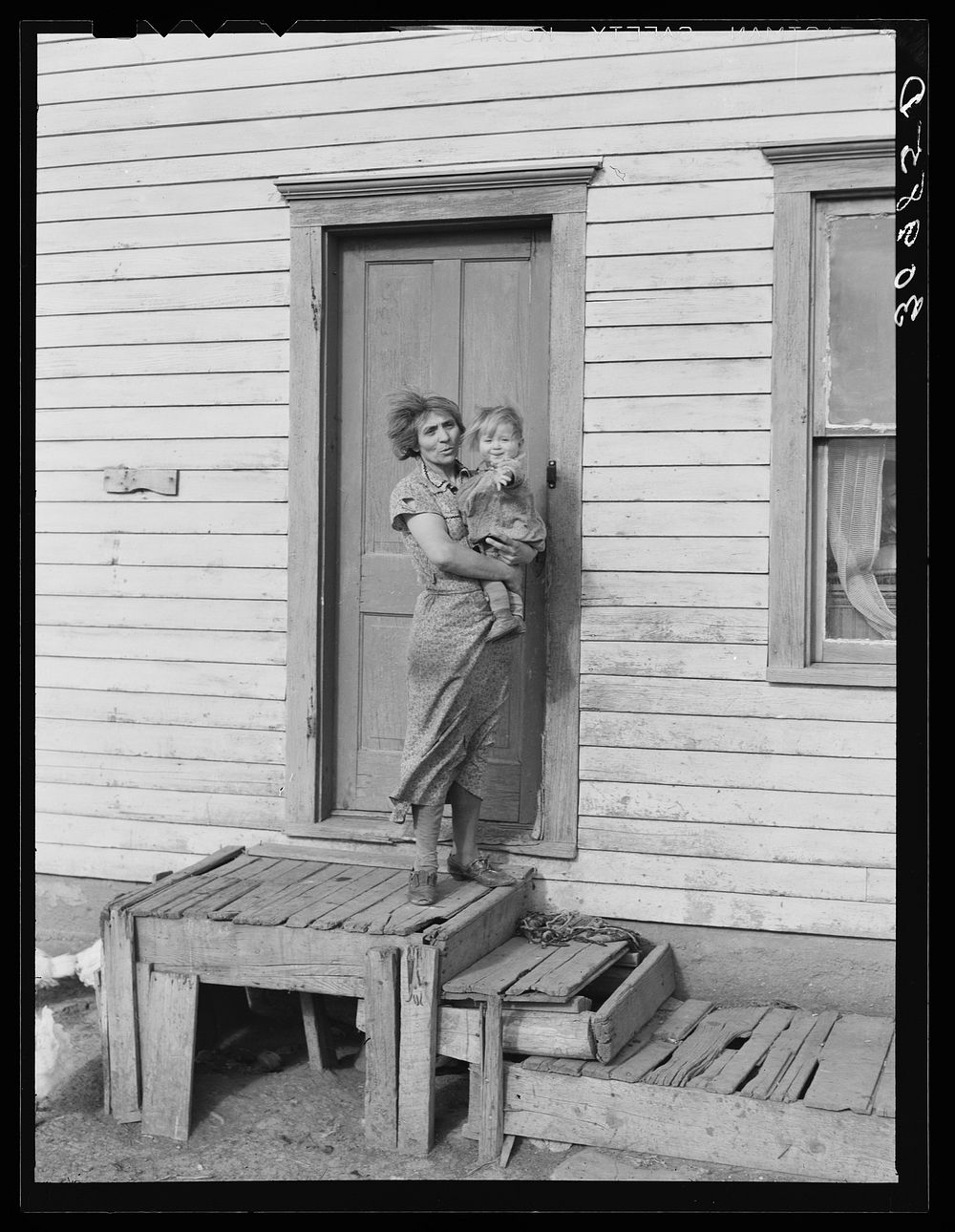 Mrs. John Baker and baby on steps of farm home. Divide County, North Dakota by Russell Lee