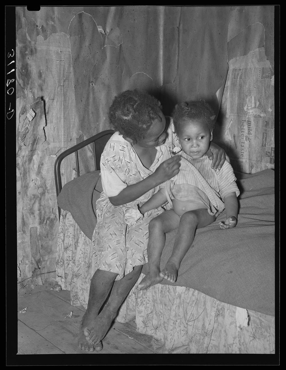 New Madrid County, Missouri. Child of sharecropper wiping baby's nose in cabin by Russell Lee