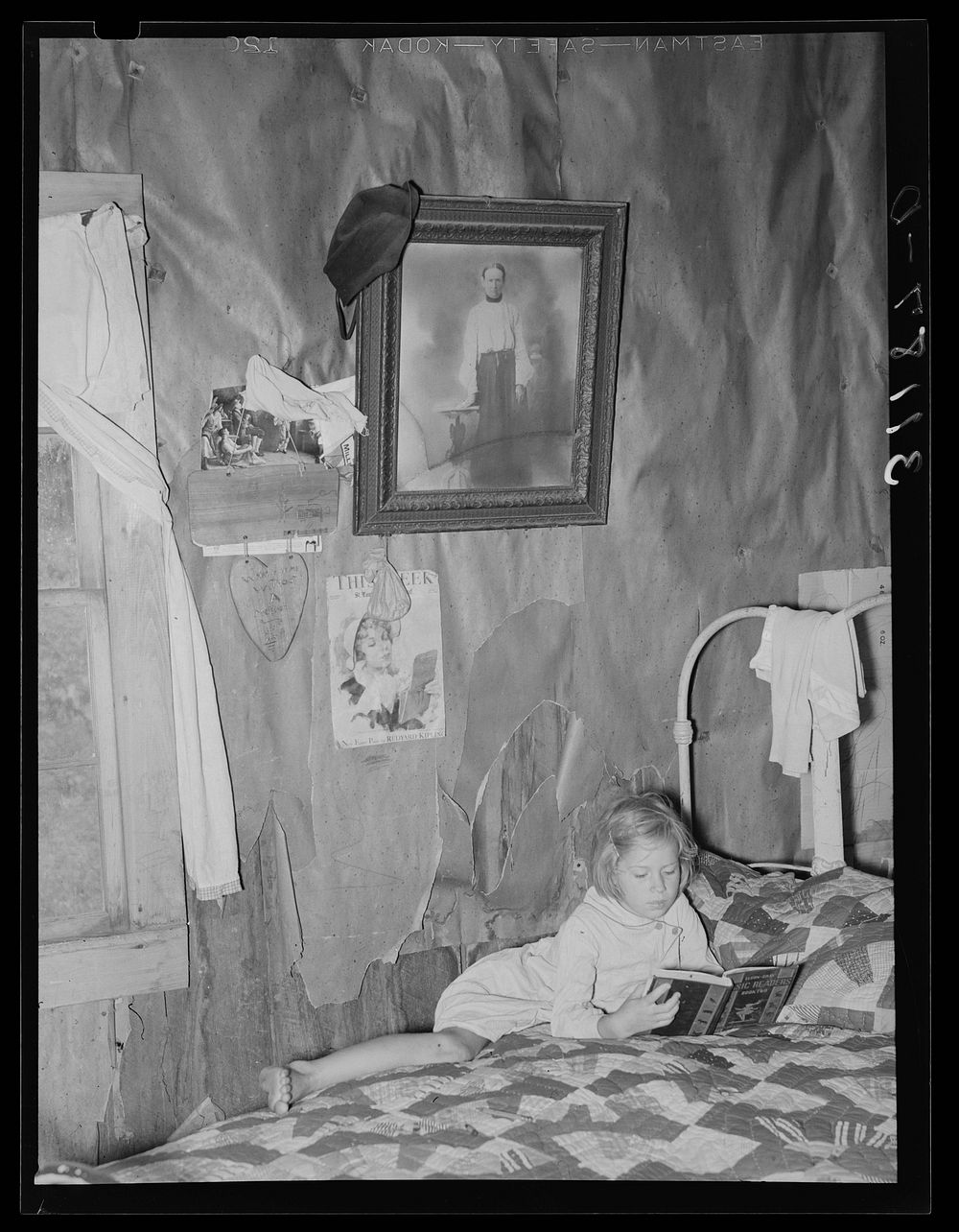 Southeast Missouri Farms. Child of sharecropper reading on bed in living room by Russell Lee
