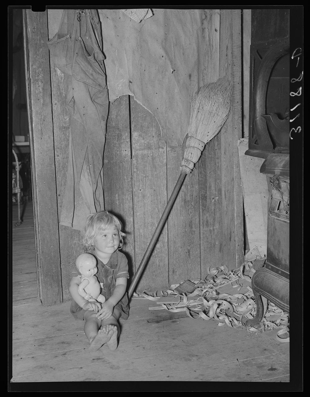 Southeast Missouri Farms. Daughter of sharecropper with doll on kitchen in shack home by Russell Lee