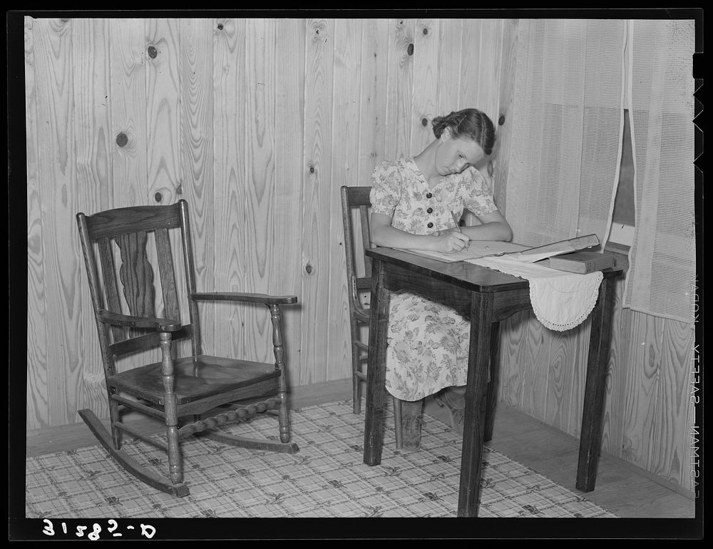 The daughter of the Atkinson family, doing her homework in corner of living room of new farm home. Southeast Missouri Farms…