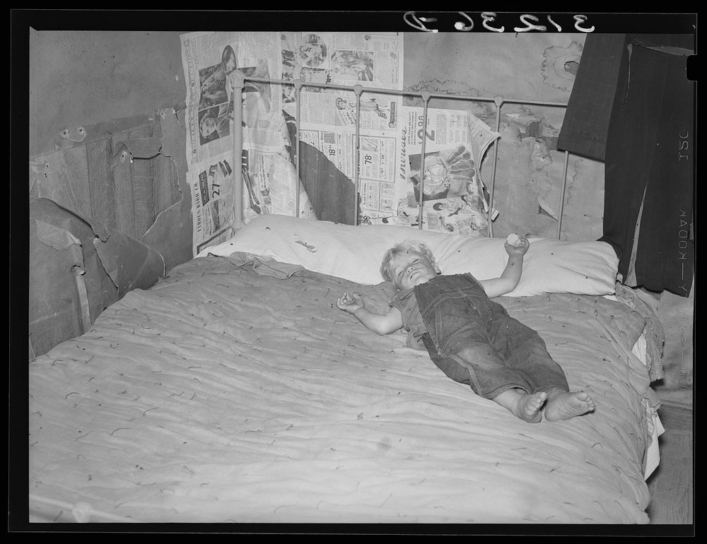 Southeast Missouri Farms. Child of FSA (Farm Security Administration) client, former sharecropper, asleep on bed in bedroom…