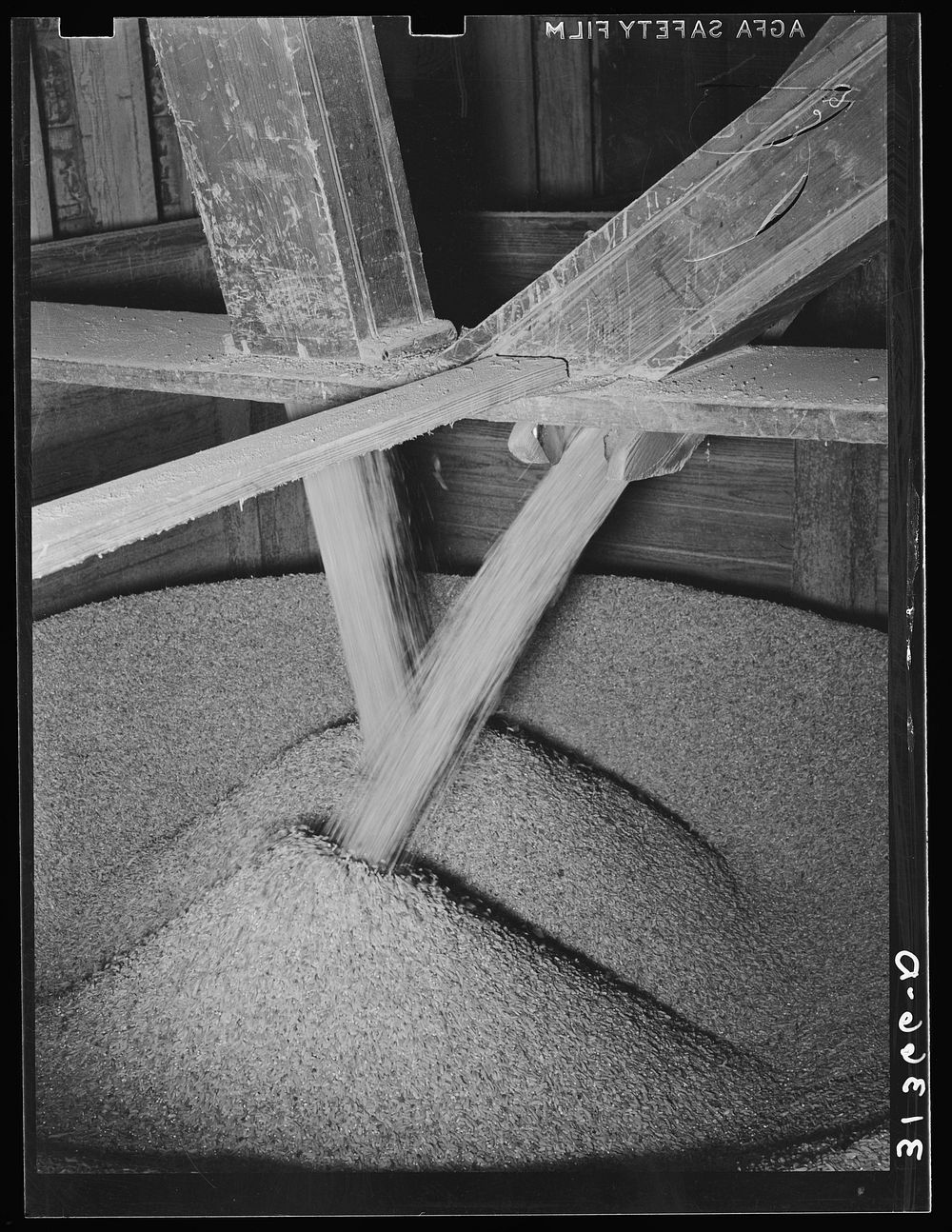 Rice pouring into chutes from storage bin. Crowley, Louisiana by Russell Lee