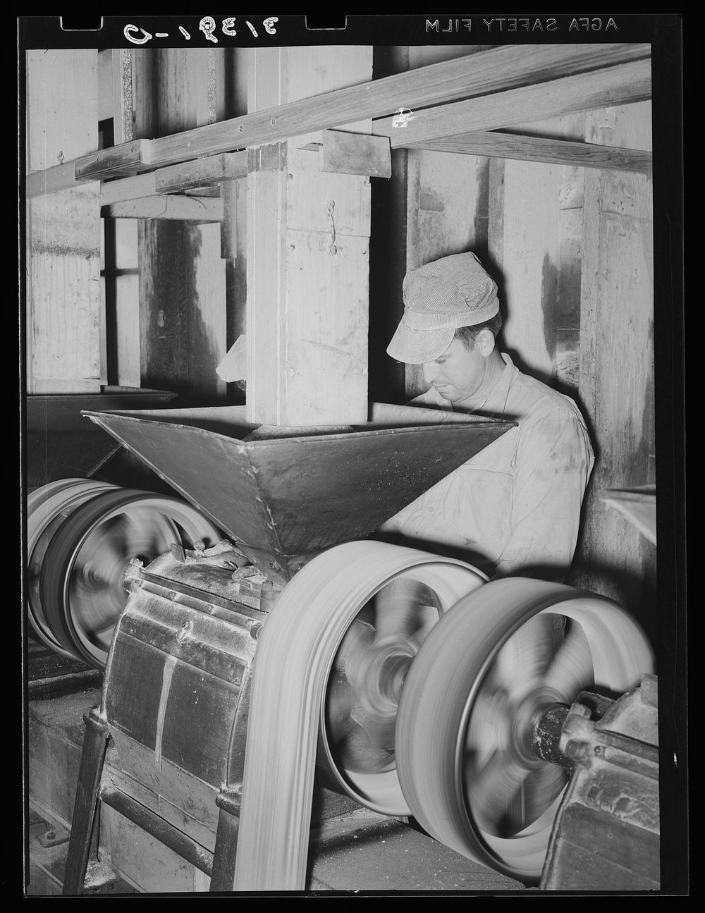 Man working at machine for removing bran from kernel. Crowley, Louisiana by Russell Lee