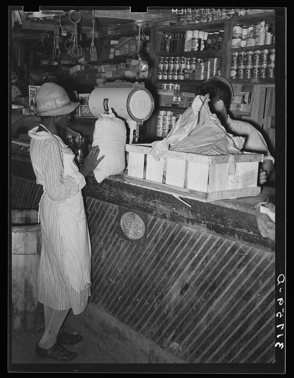  woman trading sack of pecans for groceries in general store. Jarreau, Louisiana by Russell Lee