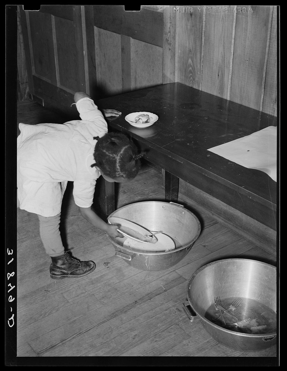 Children in nursery school at Lakeview Project, Arkansas, are taught to take the dishes from table and place them in pans…