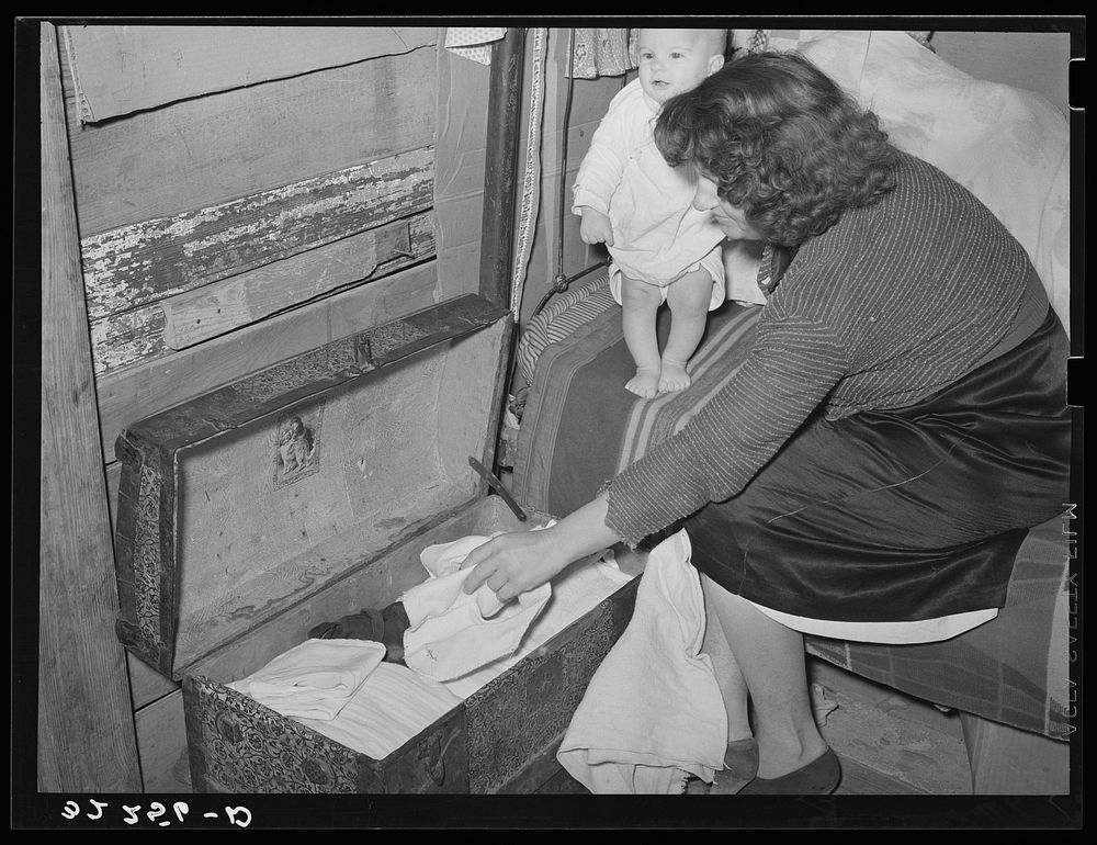 White migrant woman taking out garments for baby. Shantytown on Nueces Bay, Corpus Christi, Texas by Russell Lee