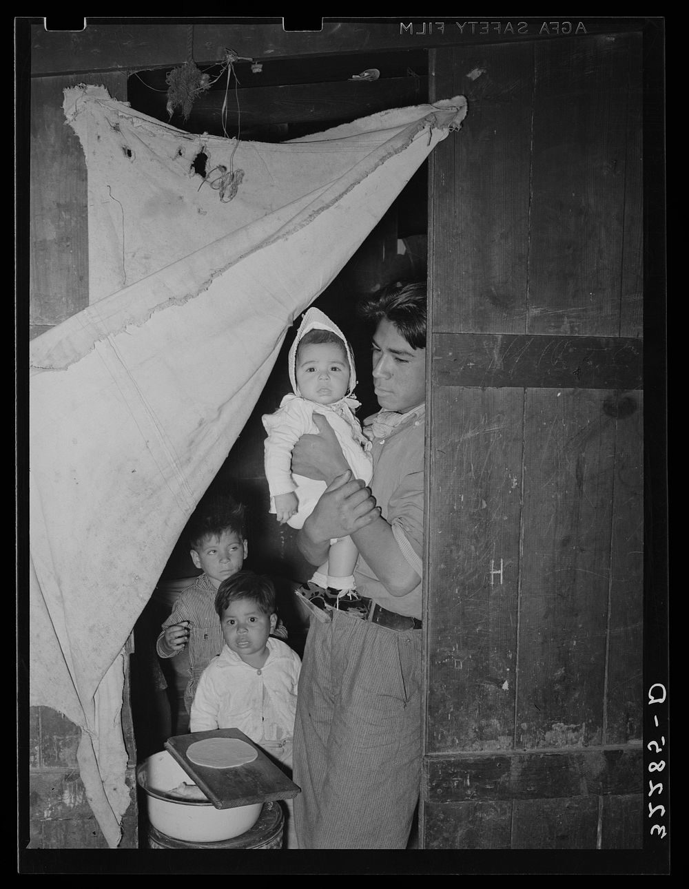 Mexican worker with children in doorway connecting two rooms of corral. Robstown, Texas by Russell Lee