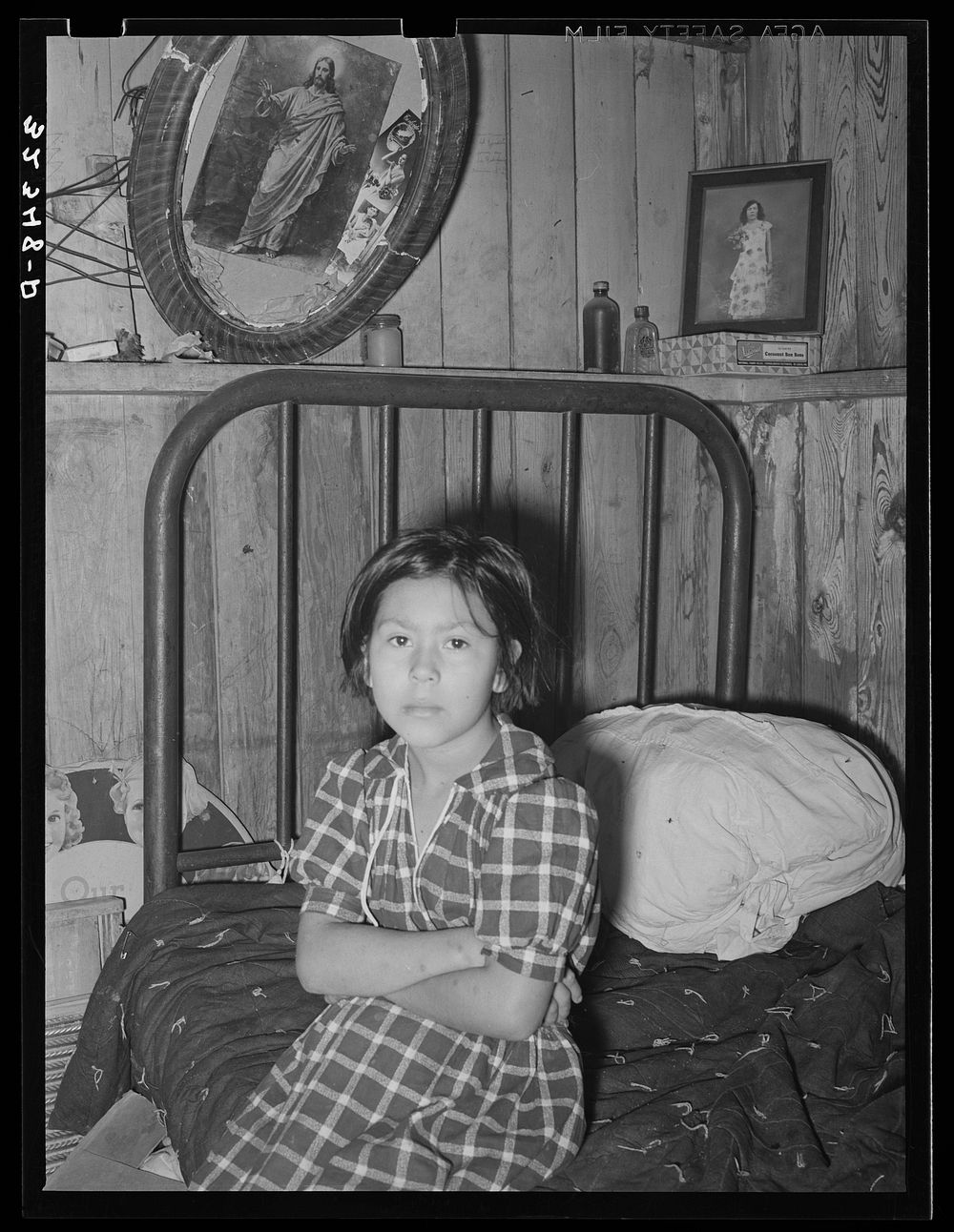 Mexican girl sitting on bed. Crystal City, Texas by Russell Lee