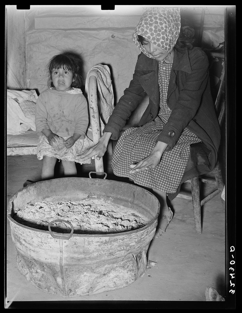 Mexican mother and child. Fires built in old galvanized tubs are used both for heat and cooking throughout the Mexican…