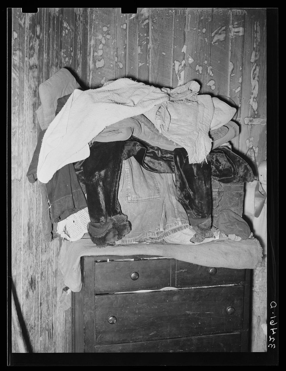 Clothing piled atop bureau in Mexican house in San Antonio, Texas. There is lack of closet space in the houses of Mexicans…