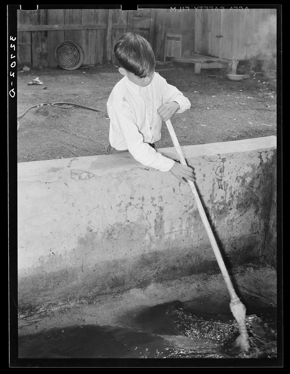 Mexican boy sweeping out vat in which pecans are soaked before cracking. They must be damp to prevent crumbling. San…