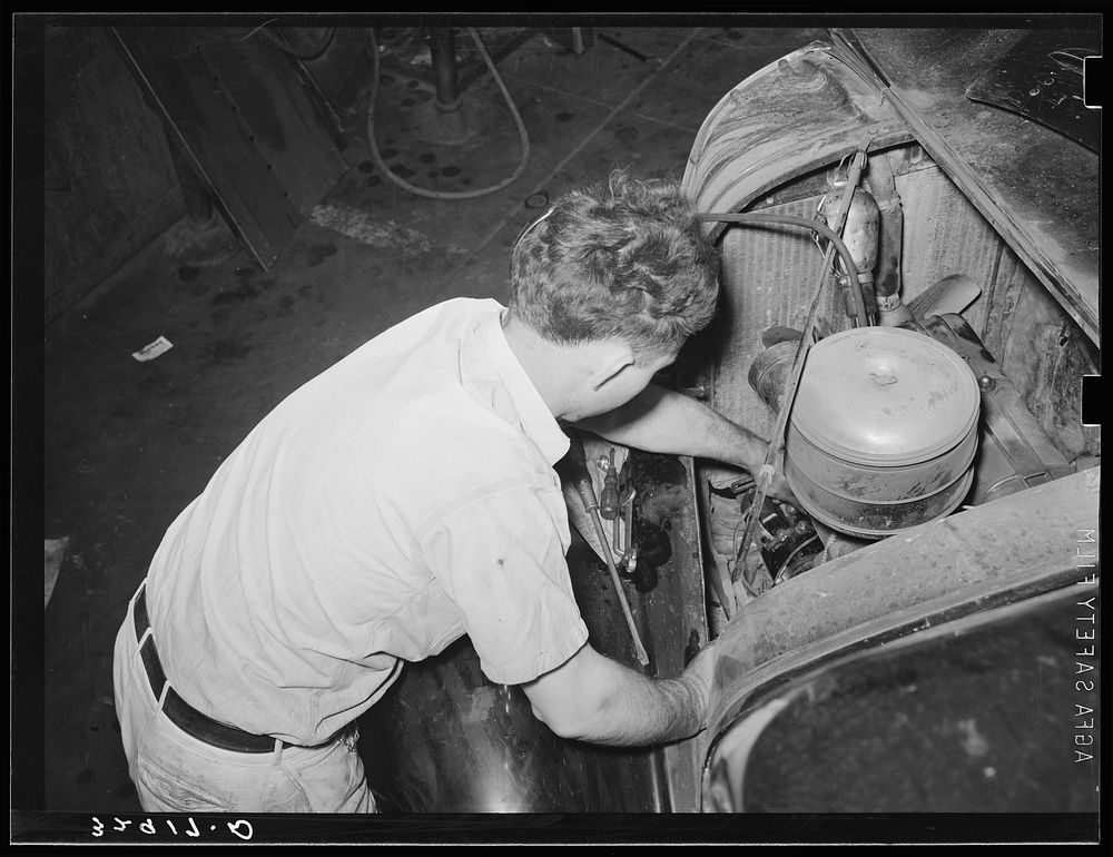 Mechanic working on motor of automobile in garage. San Augustine, Texas by Russell Lee