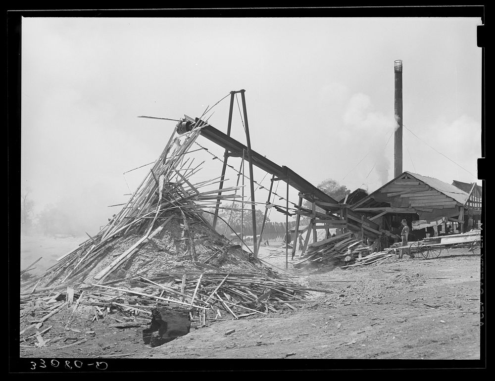 Sawmill and waste lumber pile being burned. Wells, Texas by Russell Lee