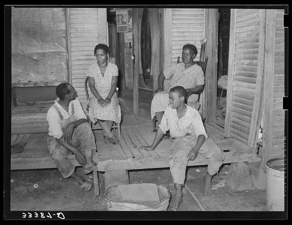Family of  agricultural day laborers sitting on the front proch of their home in Muskogee County, Oklahoma by Russell Lee