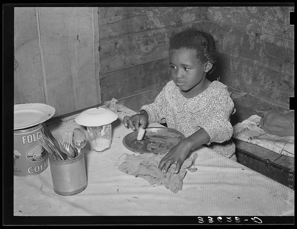 Daughter of  tenant farmer eating bread and flour gravy for dinner. Wagoner County, Oklahoma by Russell Lee