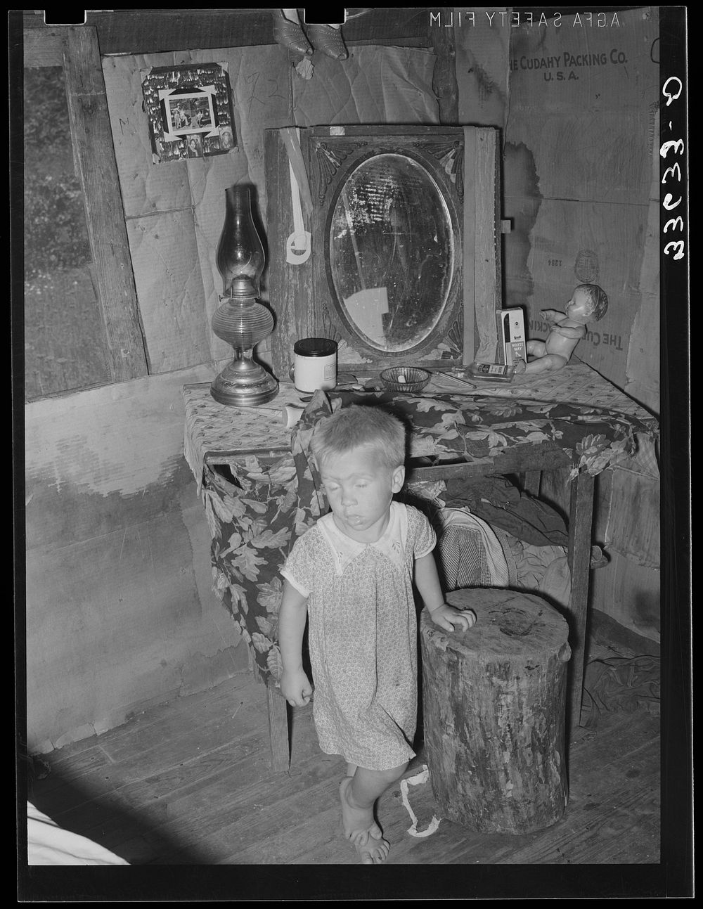 [Untitled photo, possibly related to: Child of agricultural day laborer in front of dressing table in shack. Near Vian…