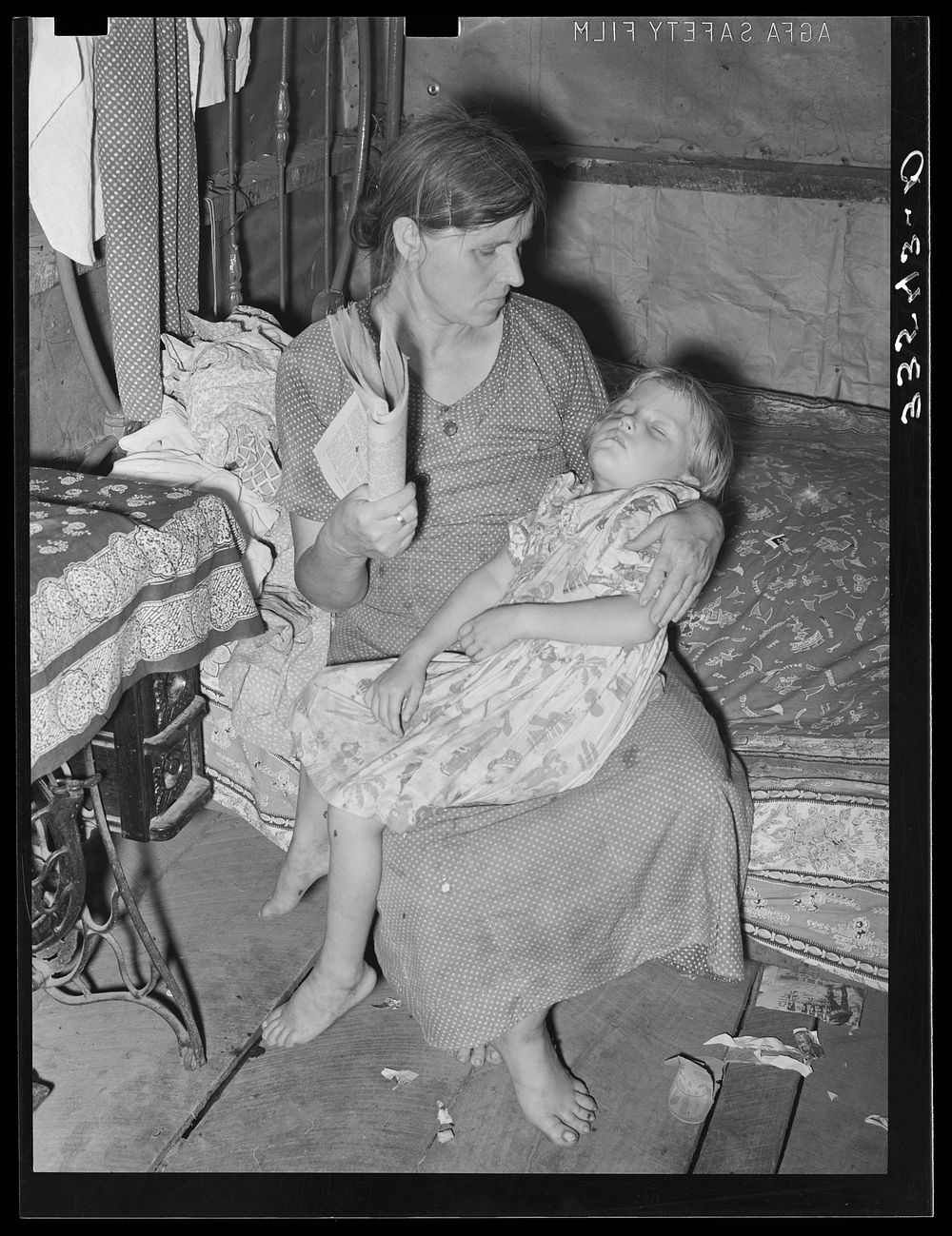 Wife and daughter of agricultural day laborer near Tullahassee, Oklahoma. She is fanning flies away from sick child. Wagoner…