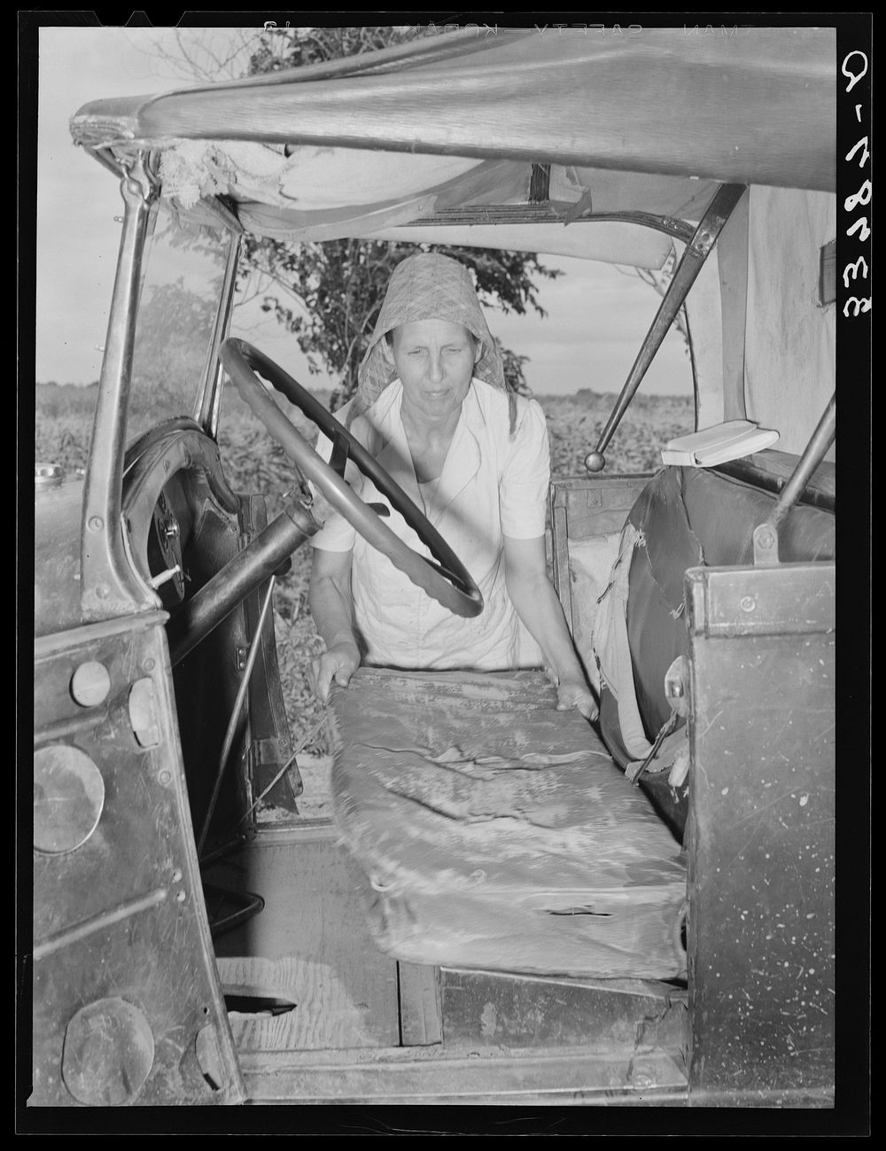 Mrs. Elmer Thomas, migrant to California, putting the front seat of their truck in place preparatory to departure from…