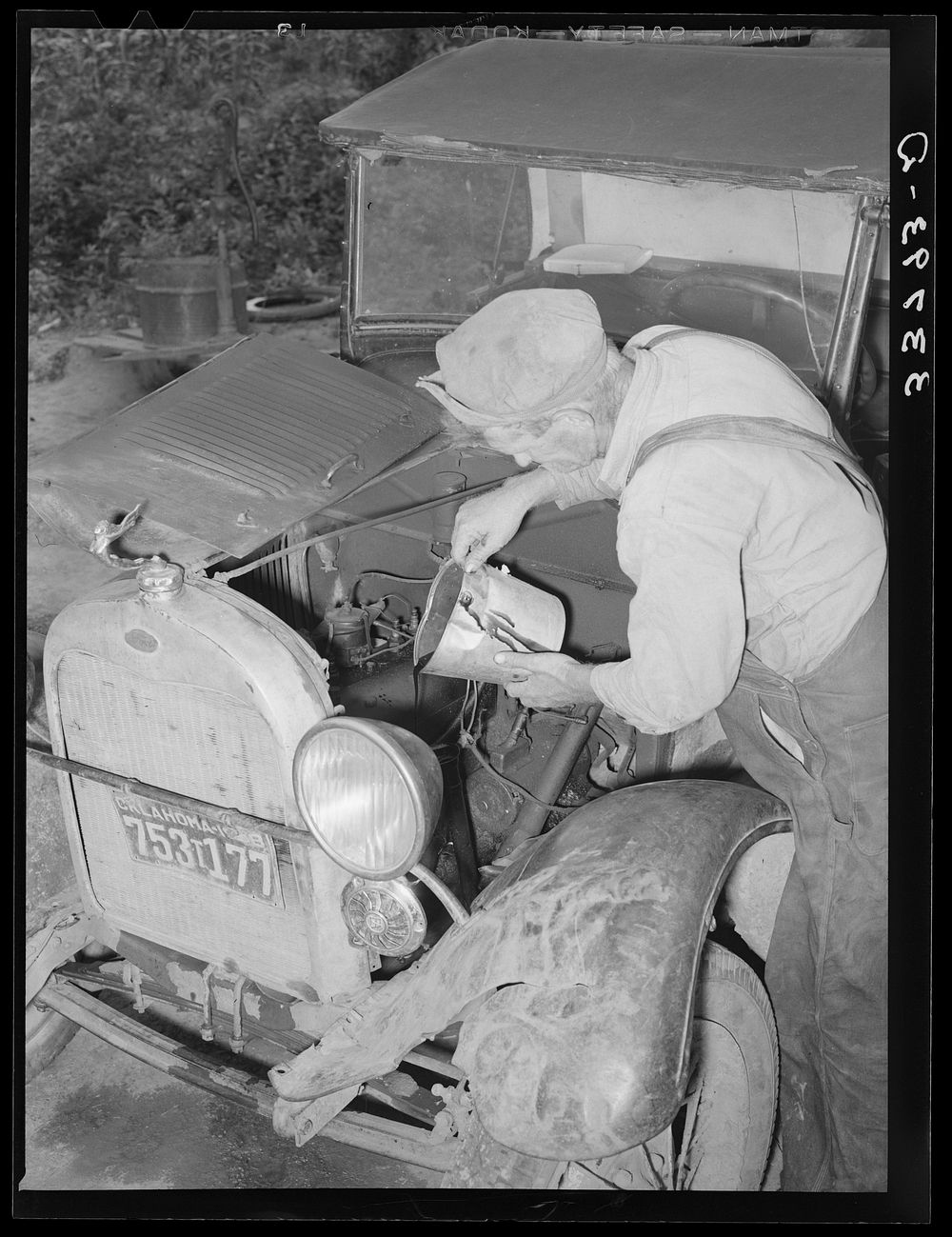 Elmer Thomas, migrant to California, pouring oil into engine preparatory for departure to California. Oklahoma by Russell Lee