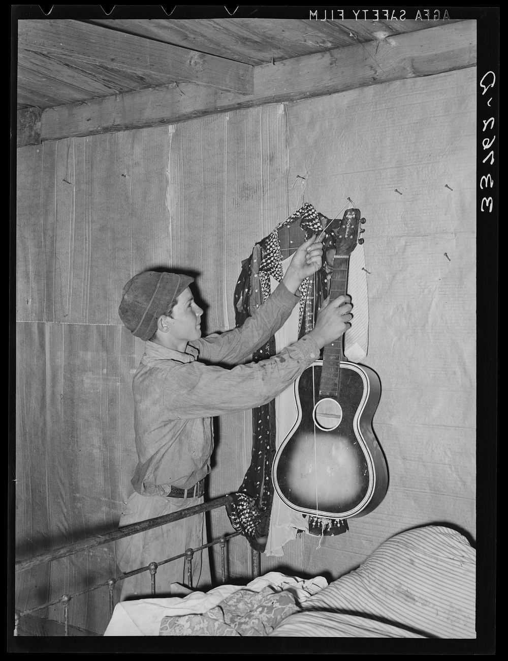 [Untitled photo, possibly related to: Migrant boy removing guitar before they leave for California. At old homestead near…