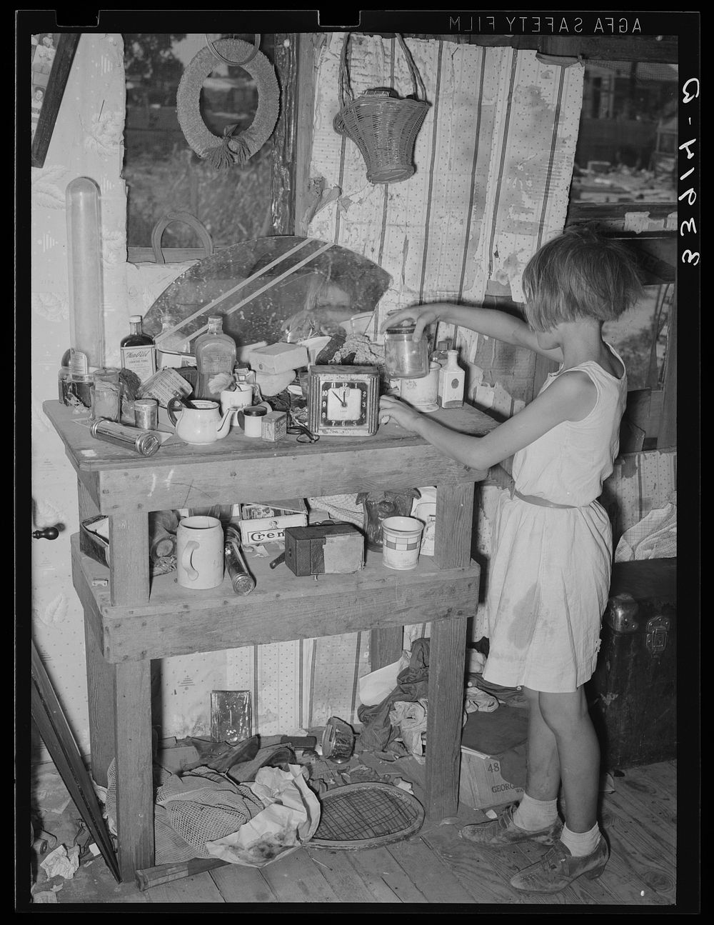 Child at cluttered table in shack home in Mays Avenue camp. Oklahoma City, Oklahoma. See general caption no. 21 by Russell…