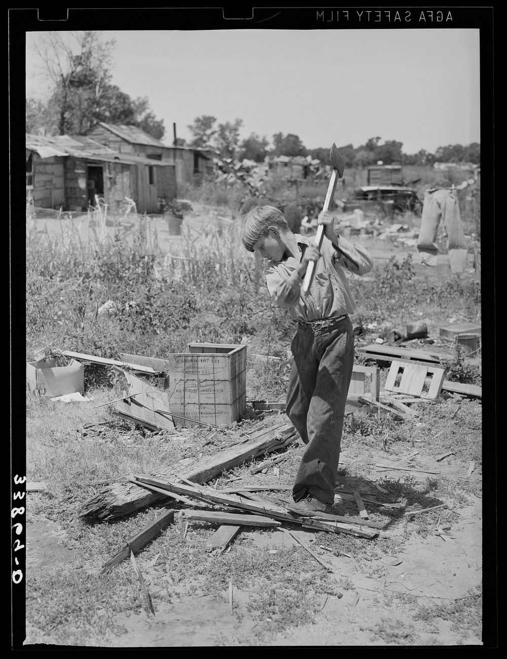 Boy living in Mays Avenue camp, Oklahoma City, Oklahoma, chopping wood.  Refer to general caption no. 21 by Russell Lee