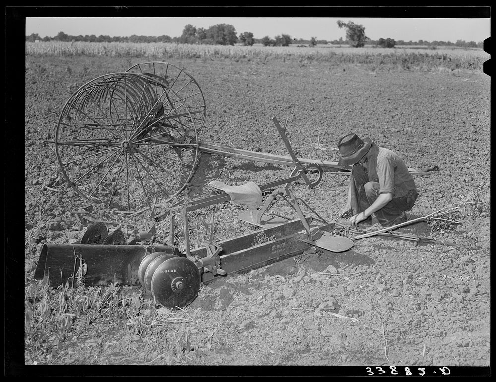 Son of tenant farmer near Muskogee, Oklahoma, working on disc harrow with rake in background. Refer to general caption no.…