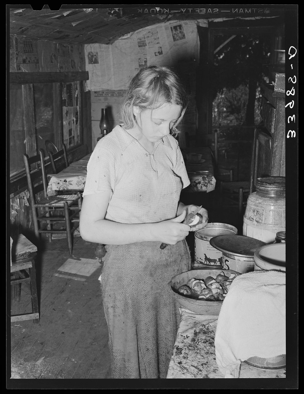 Daughter of tenant farmer peeling potatoes for noonday meal. Muskogee, Oklahoma by Russell Lee