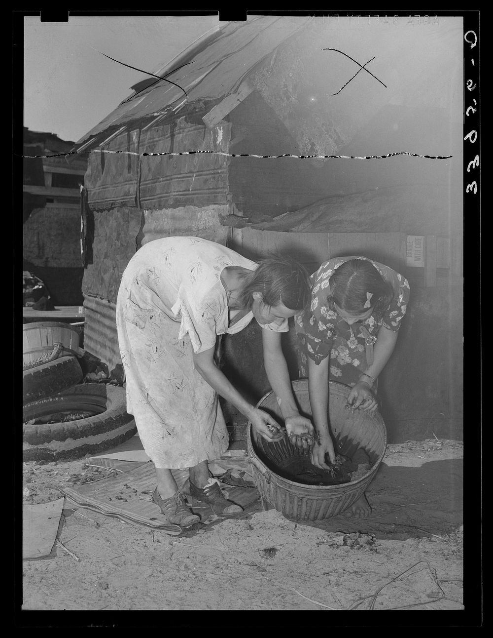 Mother and daughter picking over crawfish which they catch to sell for bait. Mays Avenue camp, Oklahoma City, Oklahoma.…