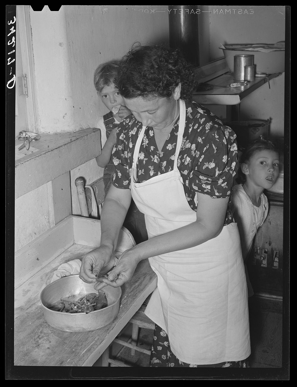 Spanish-American woman peeling peppers after the skins were loosened by heating on top of stove. Near Taos, New Mexico by…