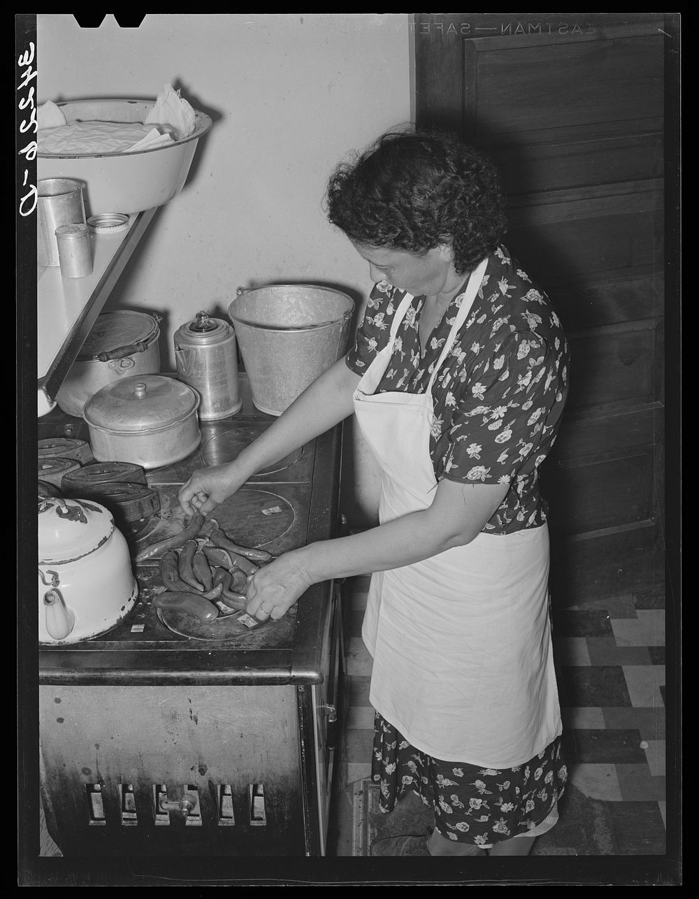 Spanish-American woman placing and turning peppers on the stove near Taos, New Mexico by Russell Lee