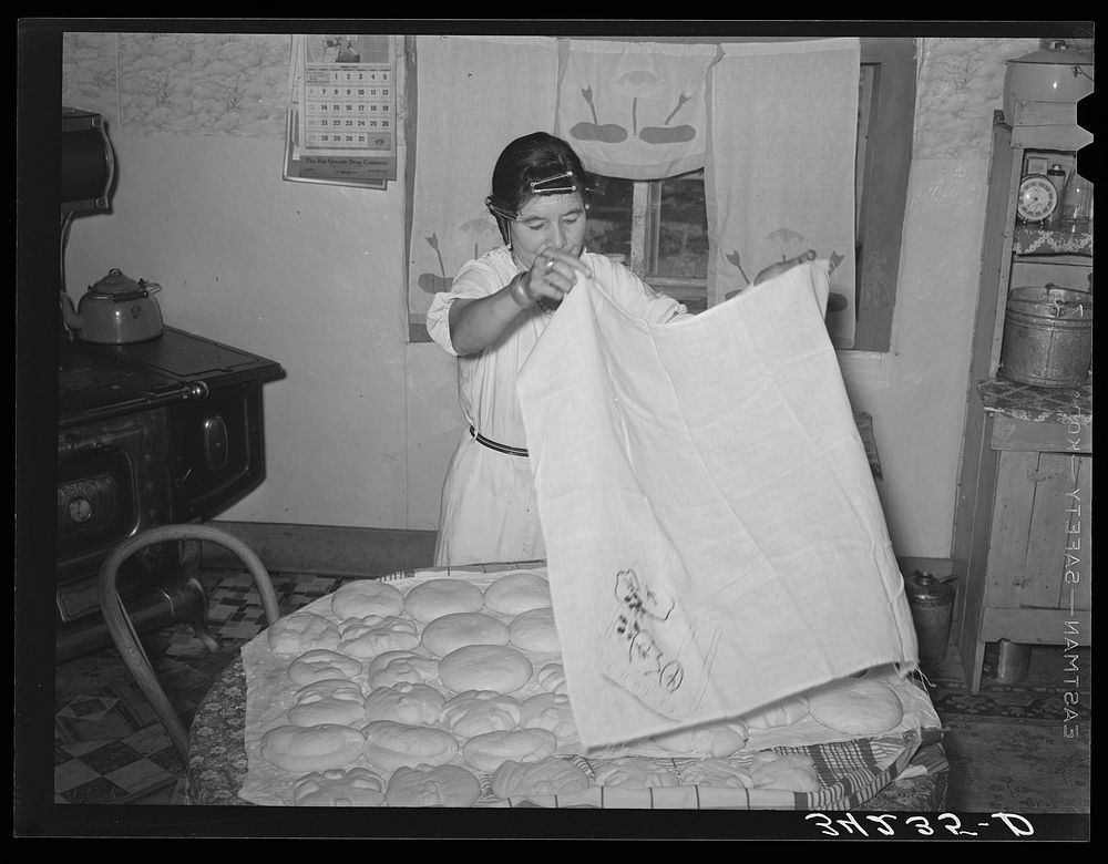 Spanish-American woman covering dough so that shaped loaves will rise evenly. Near Taos, New Mexico by Russell Lee