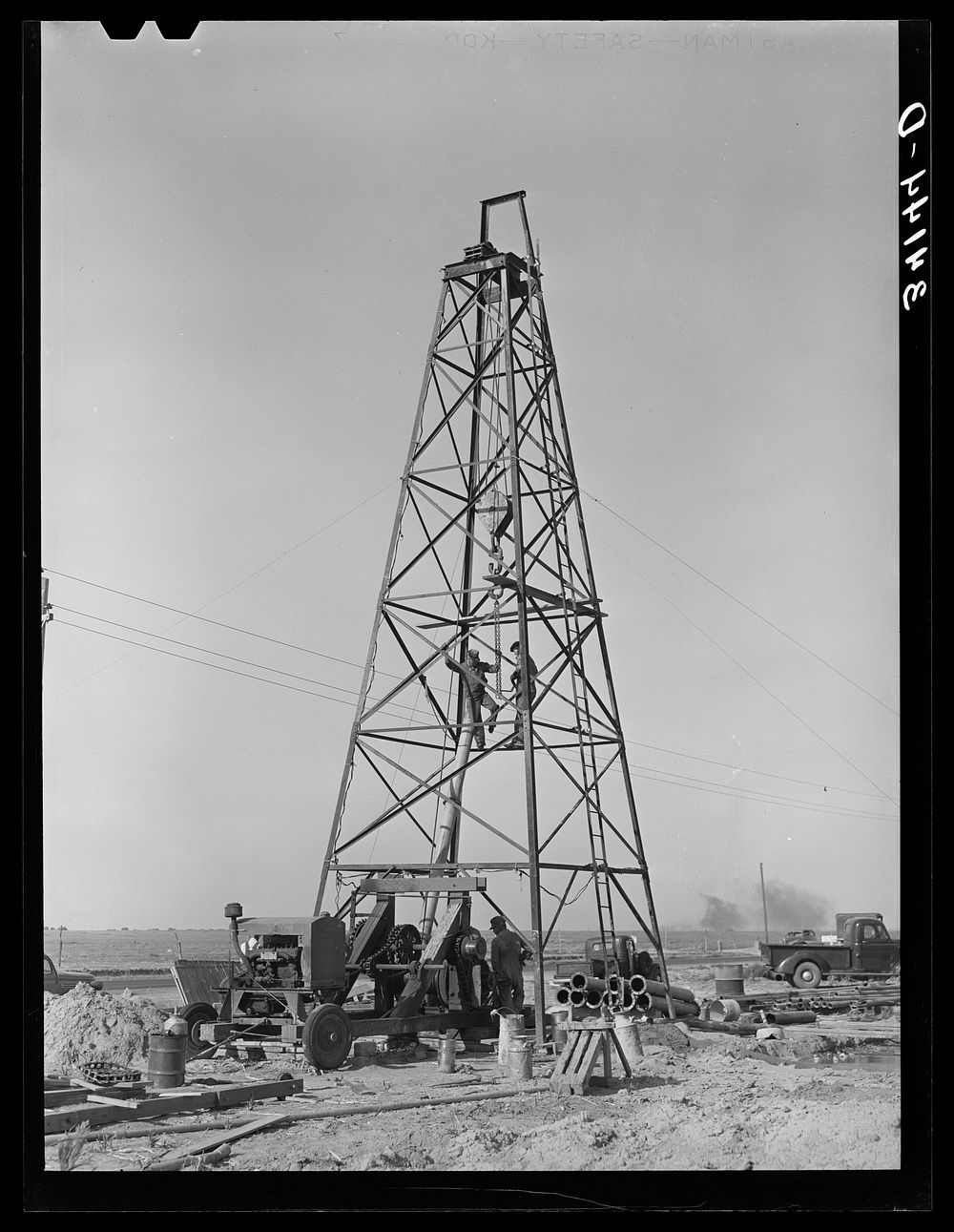 Lifting casing upon the derrick to finish a water well for irrigation purposes on farm near Garden City, Kansas by Russell…