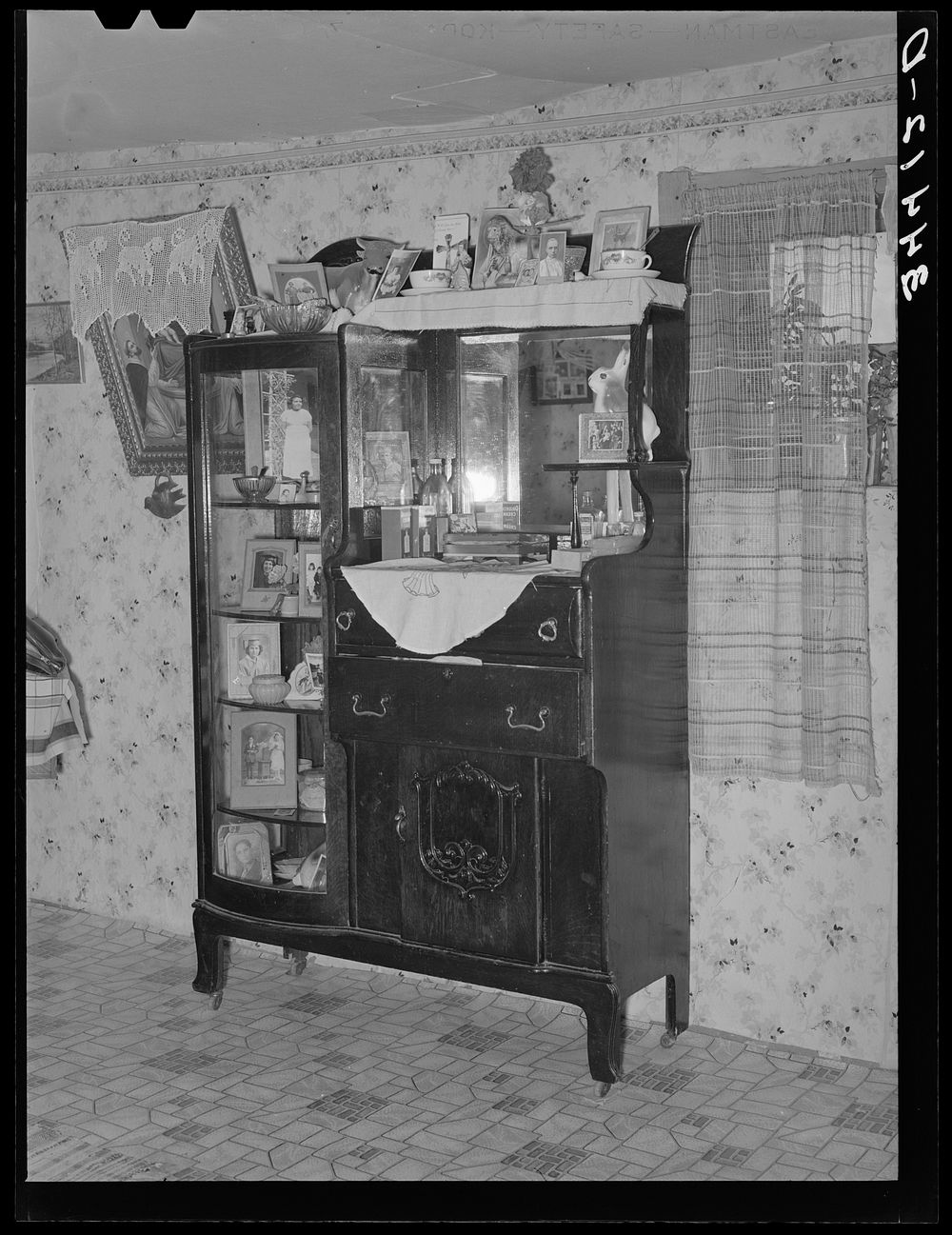Sideboard weighed down with photographs in Spanish-American home in Taos County, New Mexico by Russell Lee