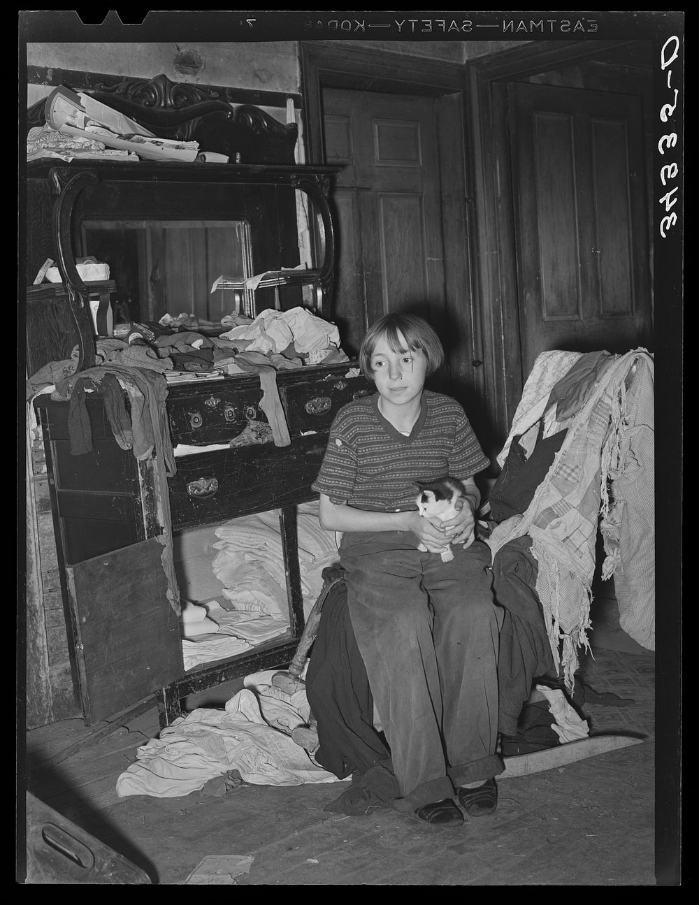 Daughter of FSA (Farm Security Administration) client sitting in front of dining room sideboard saved from a more prosperous…