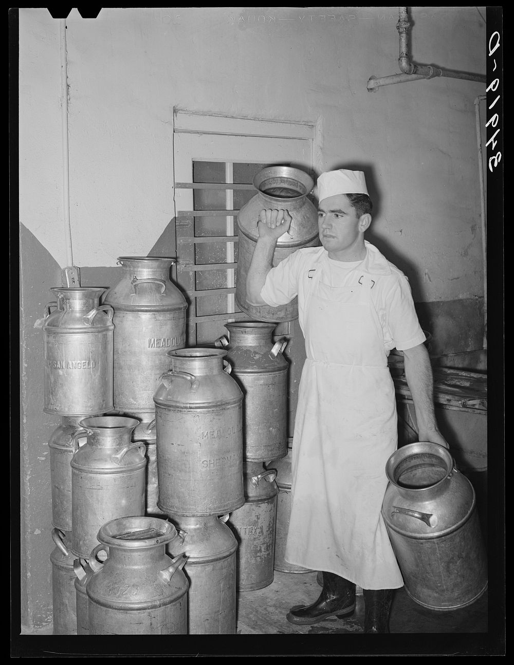 Employer at creamery carrying milk cans. Creamery, San Angelo, Texas by Russell Lee