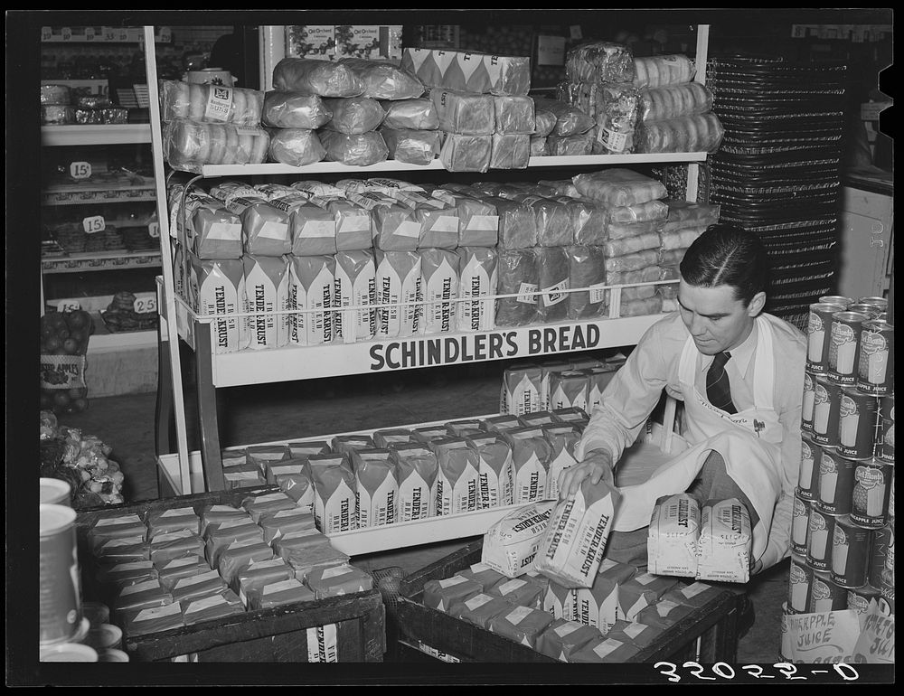 Grocery store clerk places loaves of bread on display racks. San Angelo, Texas by Russell Lee