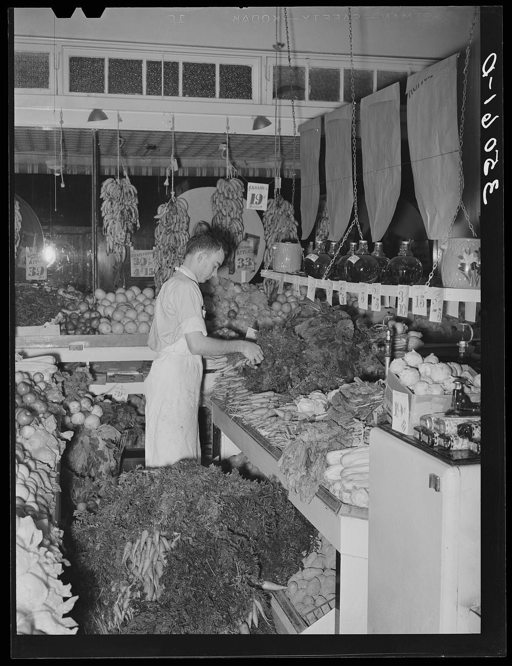 Arranging vegetables at retail grocery. San Angelo, Texas by Russell Lee