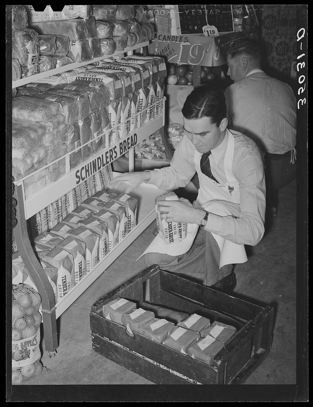 [Untitled photo, possibly related to: Grocery store clerk places loaves of bread on display racks. San Angelo, Texas] by…