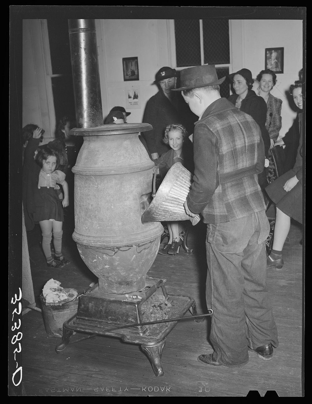 Putting coal in the stove at pie supper in Muskogee County, Oklahoma. See general caption number 24 by Russell Lee